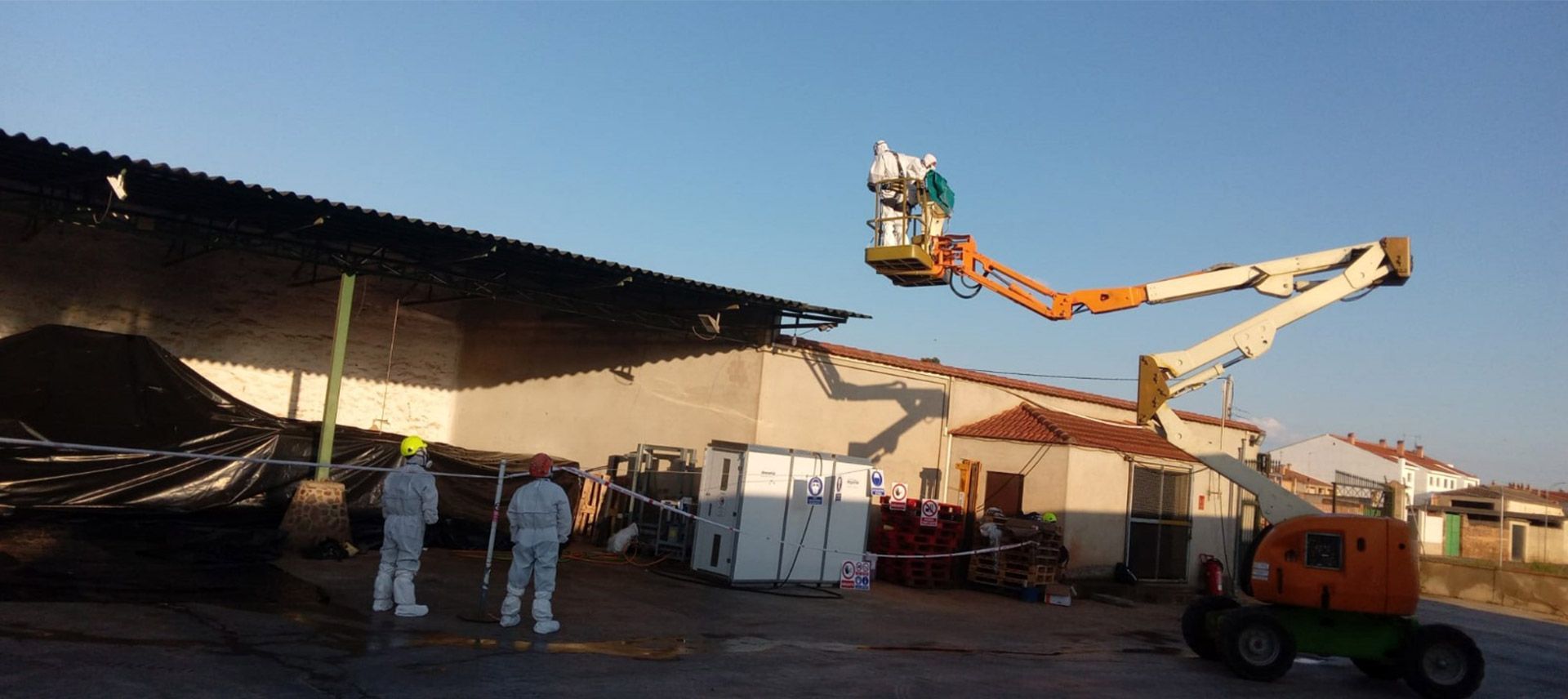 Un grupo de personas está de pie frente a un edificio con una grúa al fondo.