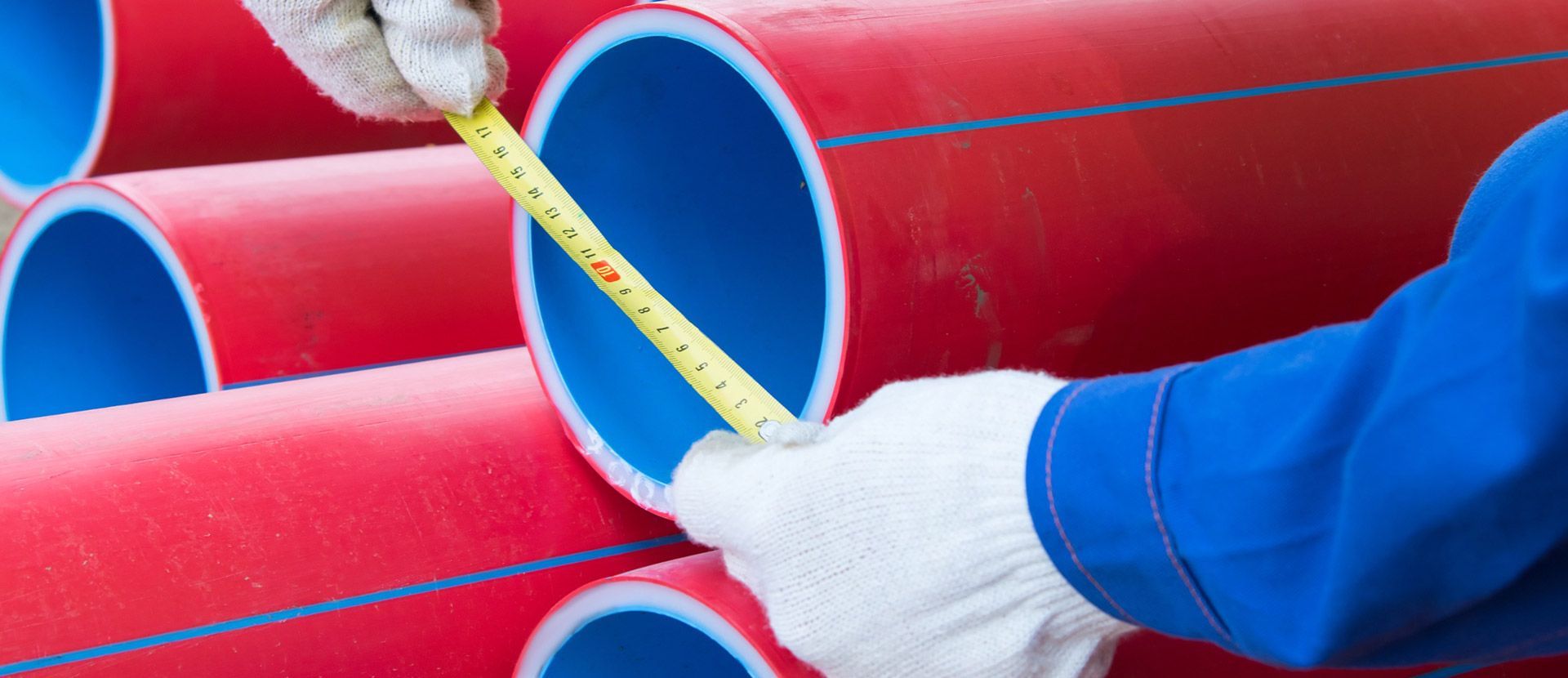 Una persona está midiendo un tubo rojo con una cinta métrica.