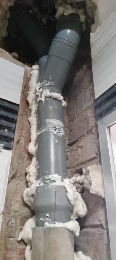 Se está instalando una tubería en un agujero en una pared.