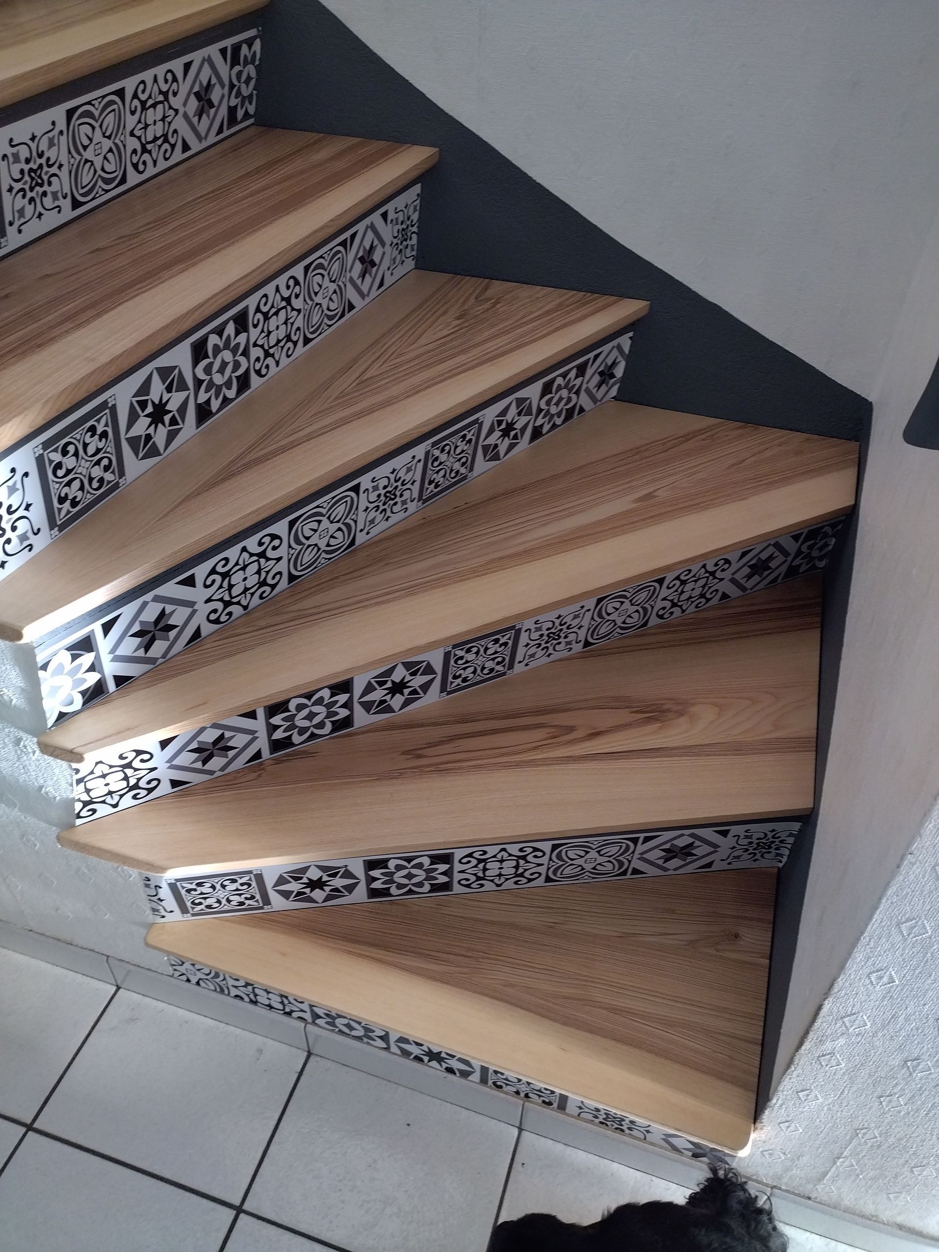 Escalier carrelé incurvé avec des marches en bois et des contremarches à motifs dans un intérieur résidentiel