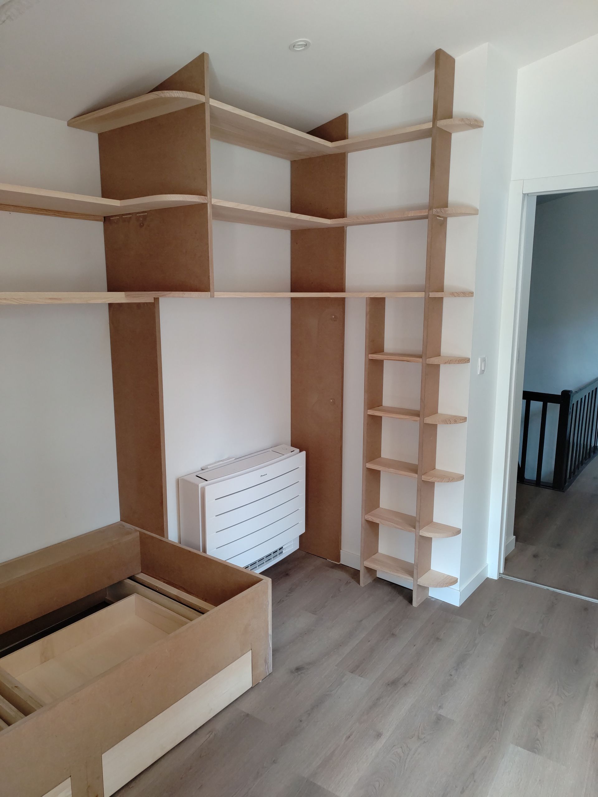 Pièce vide avec des étagères murales en bois pour chat, un radiateur blanc et un carton posé au sol