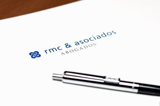 Un bolígrafo está sobre un trozo de papel que dice rmc & asociados