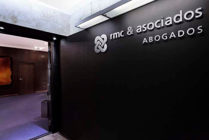 Una pared negra con las palabras rmc & asociados abogados en ella