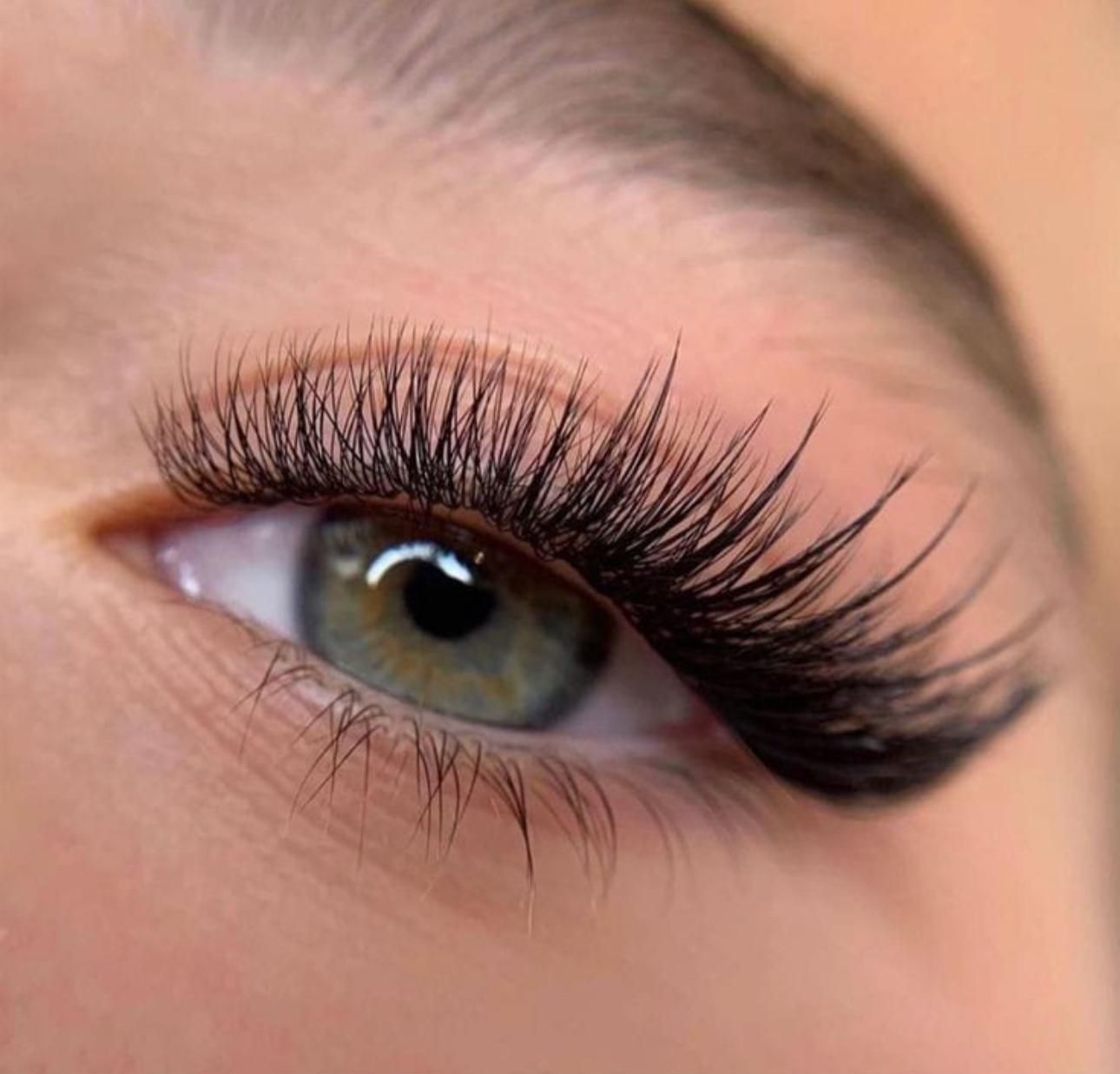 Primer plano del ojo de una persona con pestañas espesas, oscuras y largas; el ojo es verde con una ceja definida.