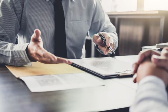 Un hombre está sentado en una mesa hablando con otro hombre.