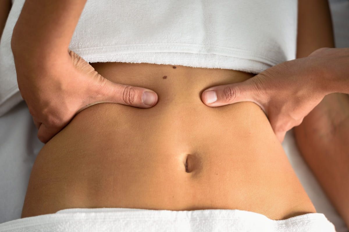 Manos presionando un abdomen desnudo durante un masaje