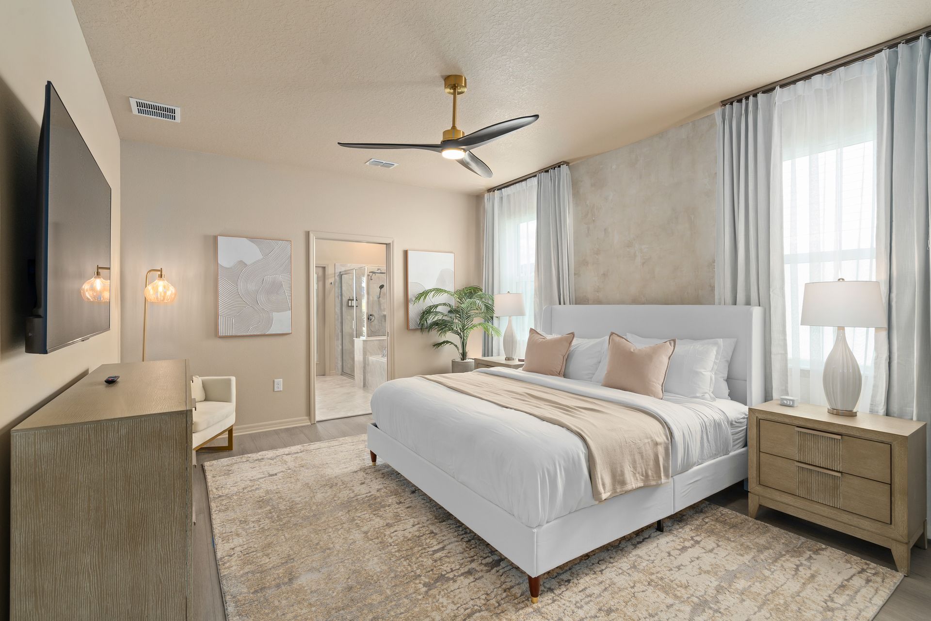 A neutral-toned bedroom with a large bed, TV, and sitting area.