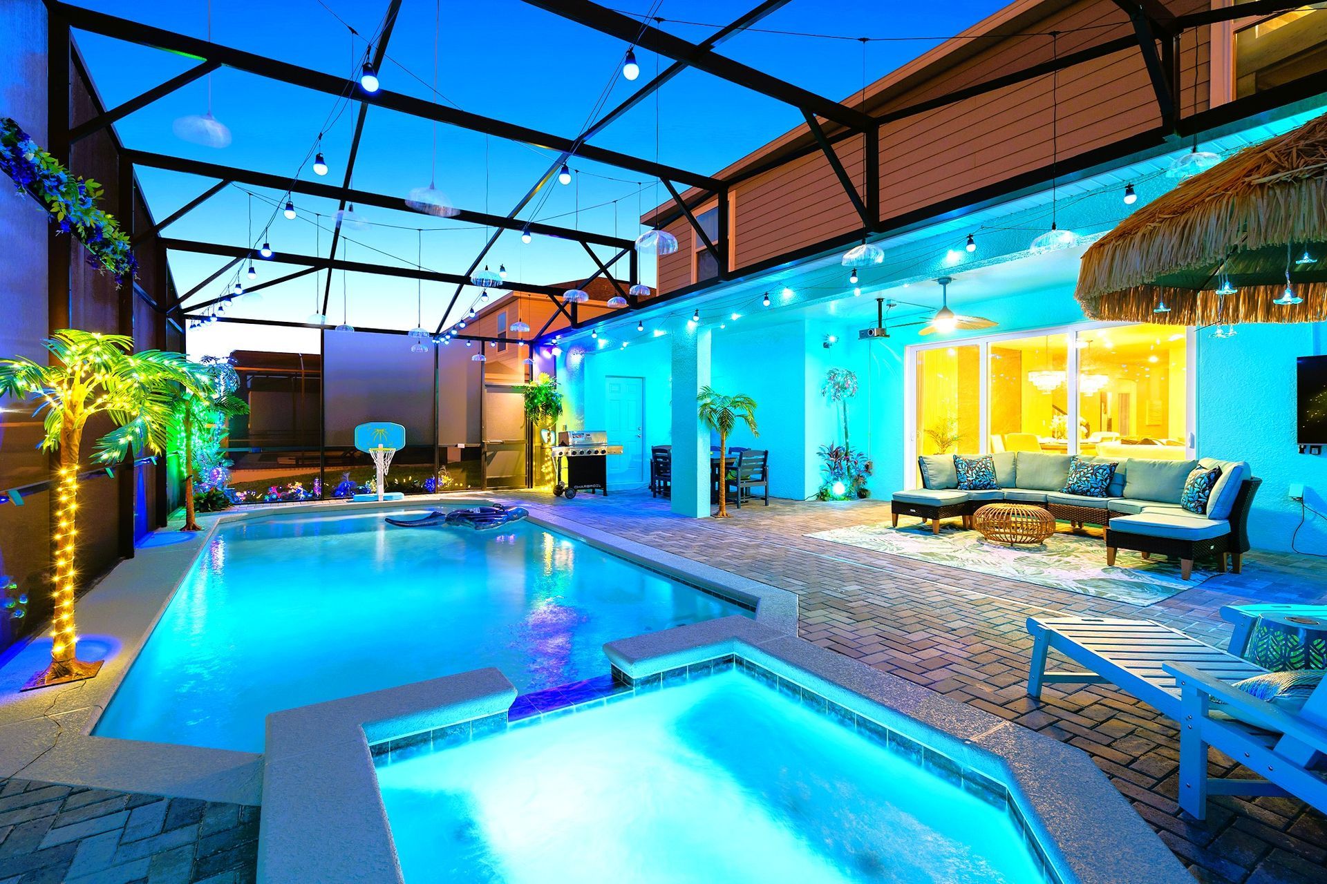 Pool area with pool, hot tub, seating, and lighting, illuminated in blue and yellow tones. Windsor Cay Resort