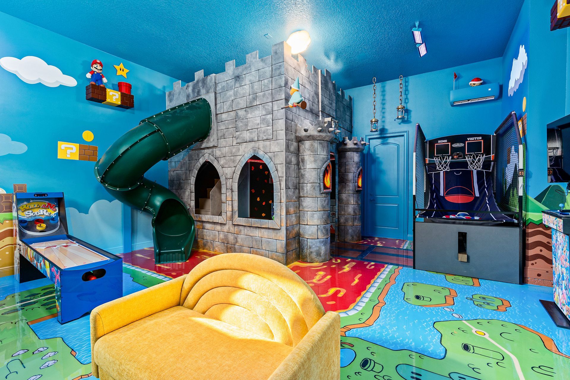 Playroom: Mario-themed castle structure with slide, arcade games, yellow chair, blue walls and carpet.