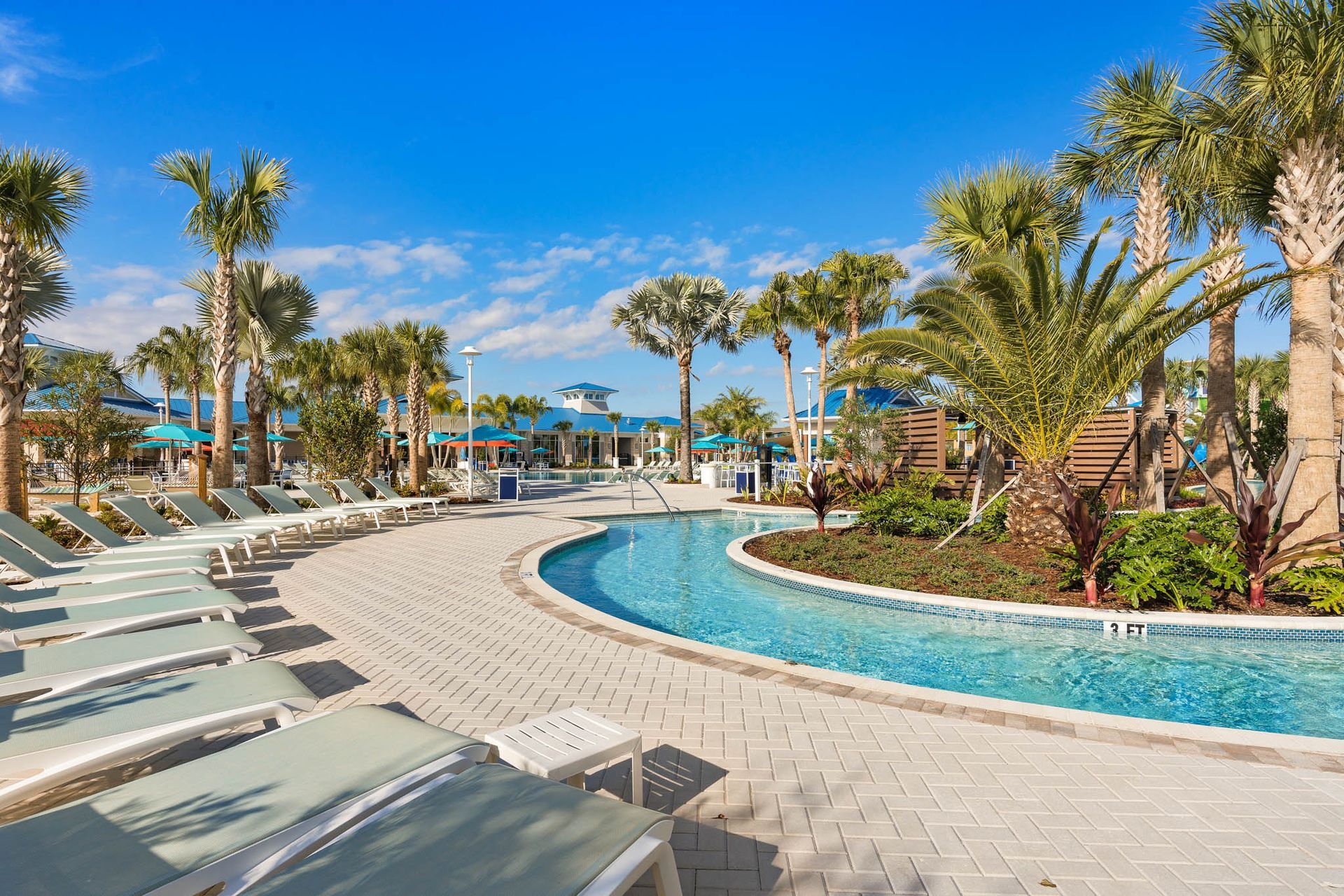 Pool with palm trees, lounge chairs, and blue sky.