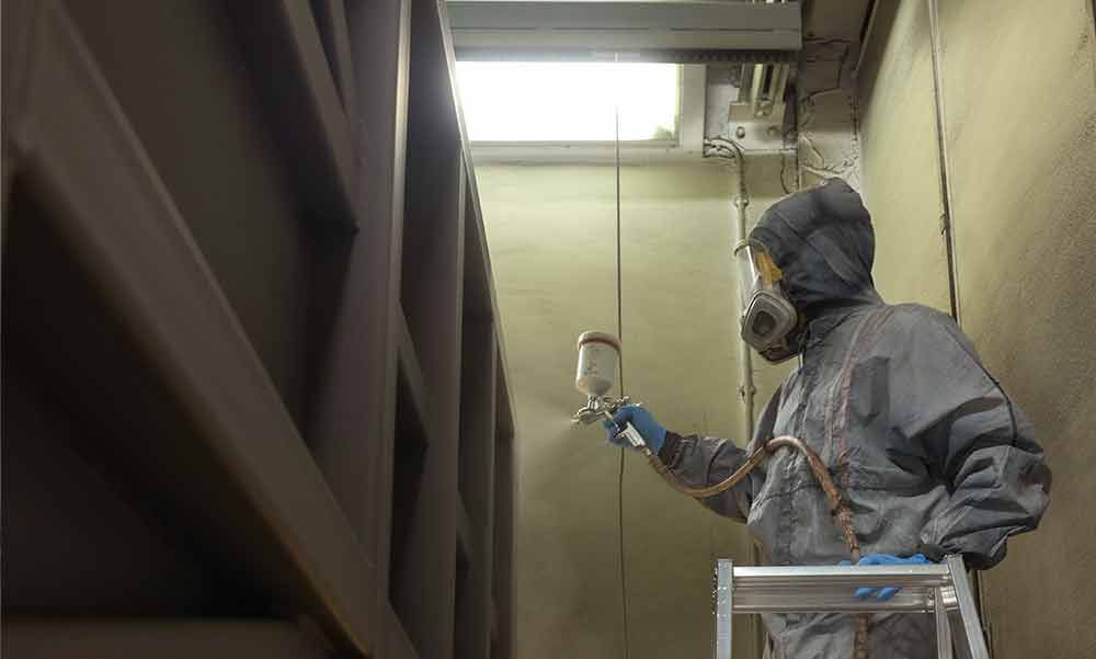 Ein Mann mit einer Gasmaske besprüht eine Wand mit Farbe.