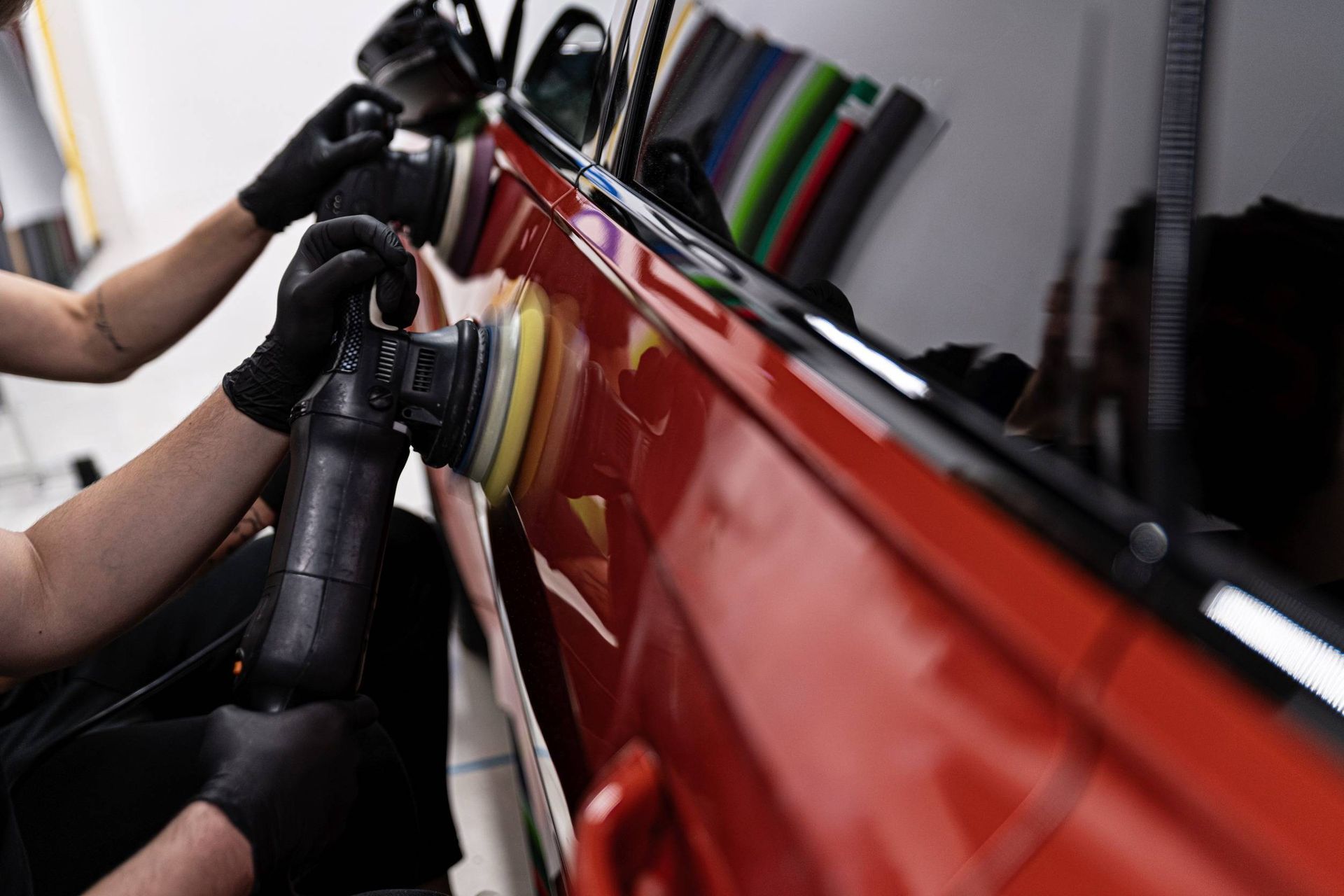 Una persona está puliendo un coche rojo con una máquina.