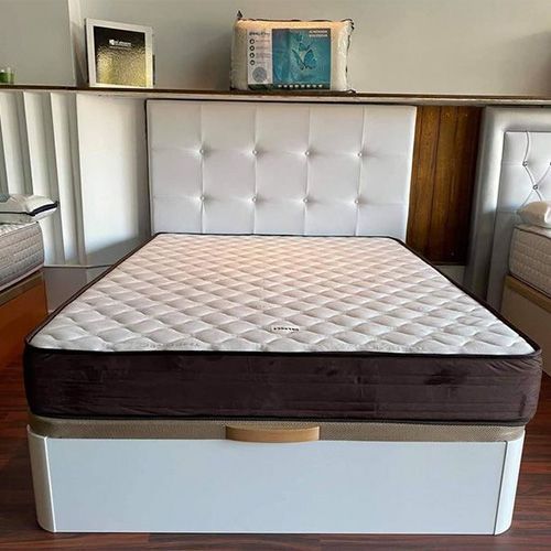 Una cama con un colchón y un cabecero en un dormitorio.