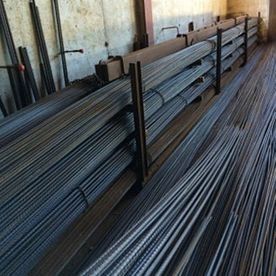 Pilas de barras de acero corrugado apiladas y almacenadas en un pasillo de un almacén.