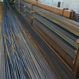 Pilas de largas varillas metálicas almacenadas en un pasillo de un almacén.