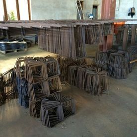 Estructuras metálicas oxidadas apiladas en filas dentro de un espacio que parece un taller.