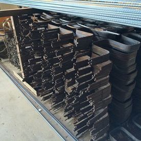 Pilas de bandejas de plástico negro almacenadas en un carrito de metal en un pasillo de un almacén.