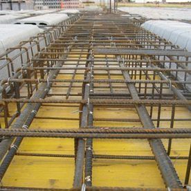 Estructura de barras de refuerzo sobre paneles de encofrado amarillos en una obra de construcción, vista desde arriba.