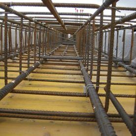Dentro de un andamio de acero con forma de túnel, con filas de vigas de color óxido y un suelo amarillo, visto en perspectiva.