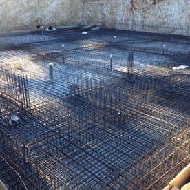 Malla de barras de refuerzo y cimientos de hormigón en construcción en una zanja.