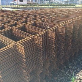 Pilas de rejillas de barras de acero de color óxido en una obra de construcción.