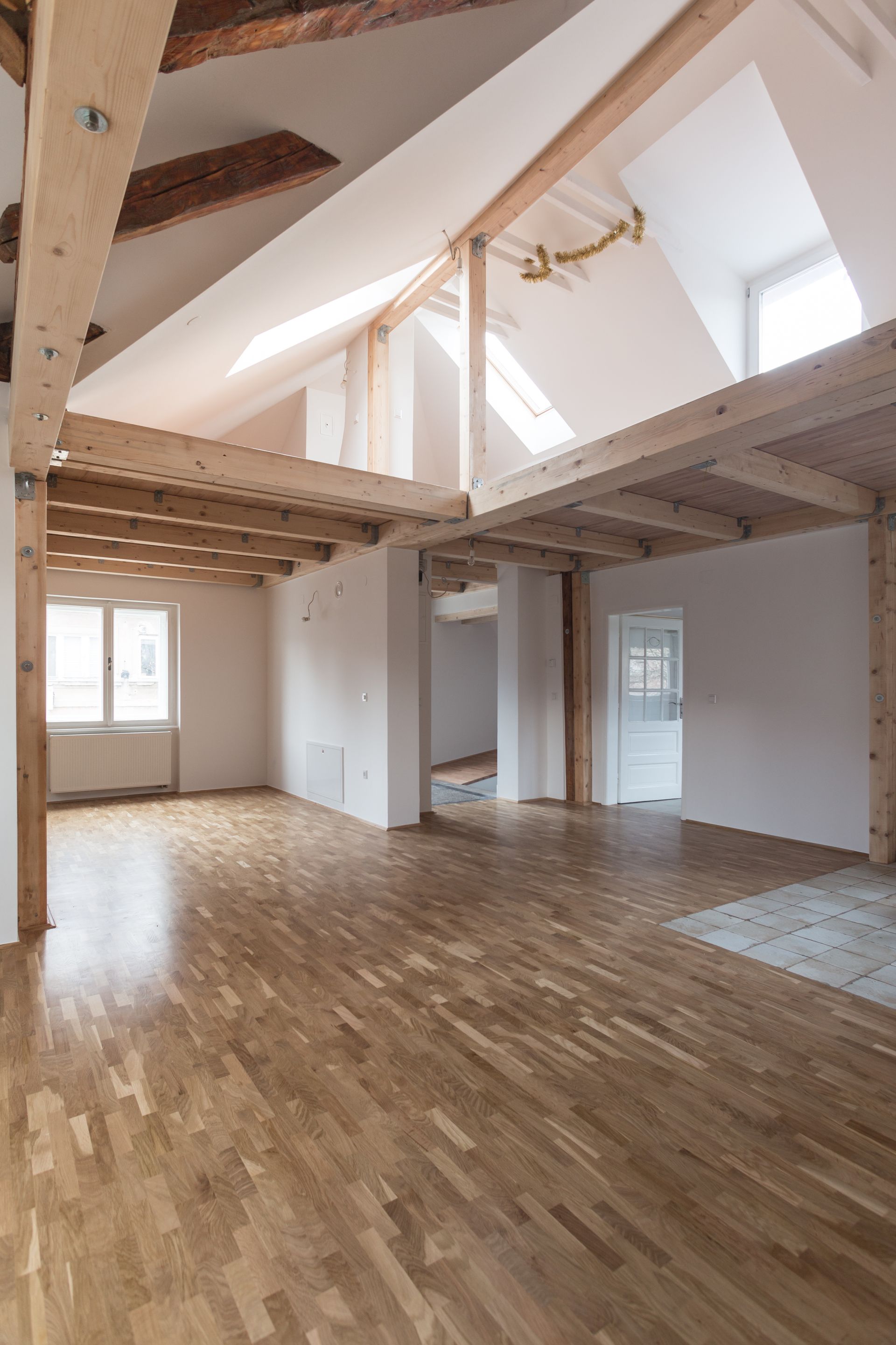 Intérieur d'une maison en rénovation, avec poutres apparentes, parquet et lumière naturelle.