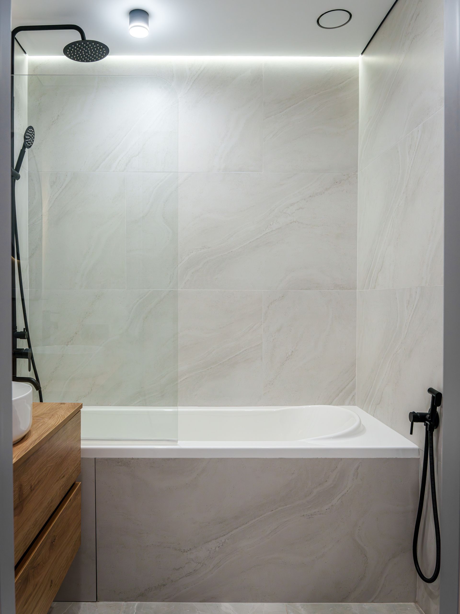 Puits de lumière avec des stores à lamelles, projetant des ombres rayées sur un mur blanc dans une pièce sombre.