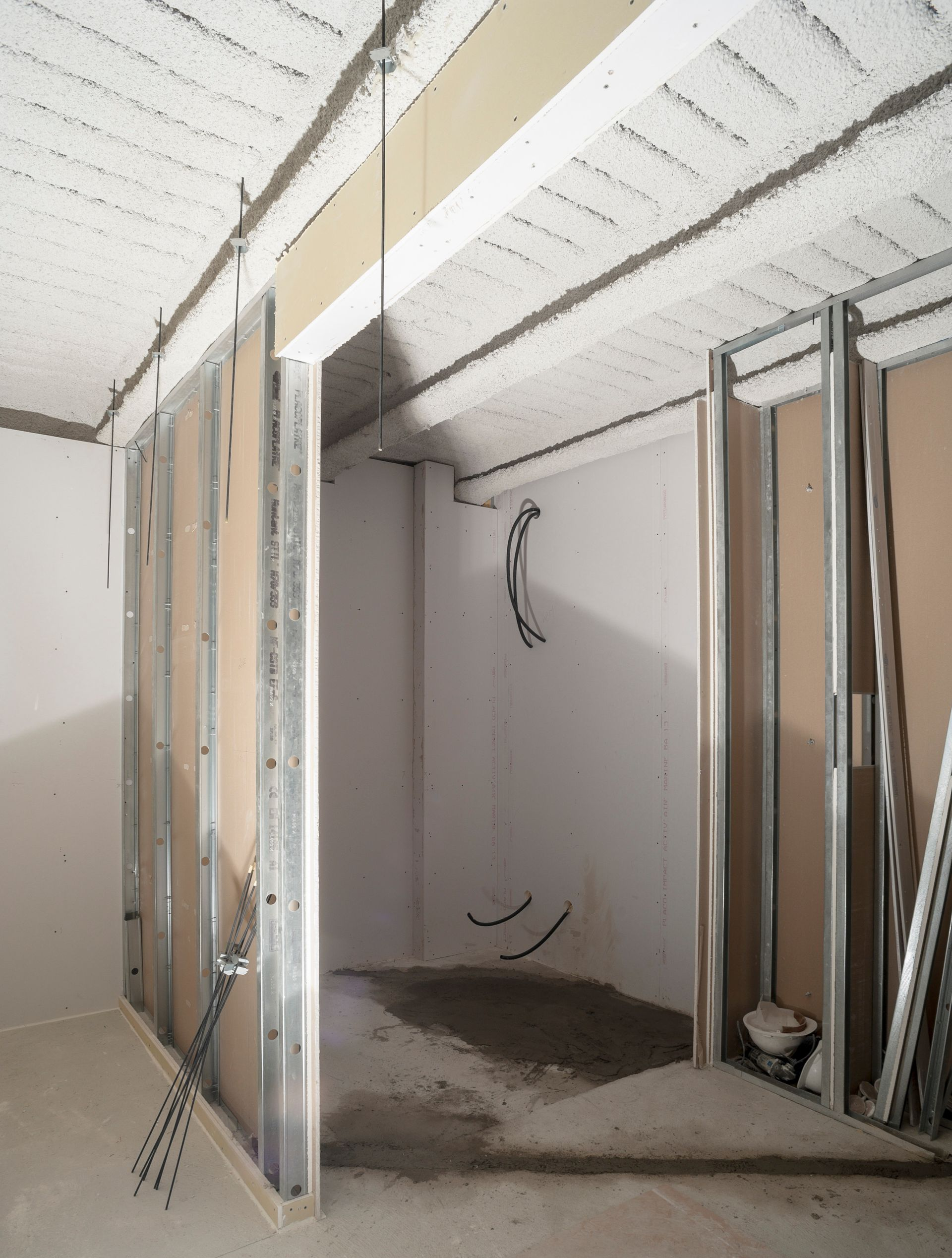 Intérieur d'une pièce en construction, avec des montants métalliques apparents, des cloisons sèches et un plafond non fini.