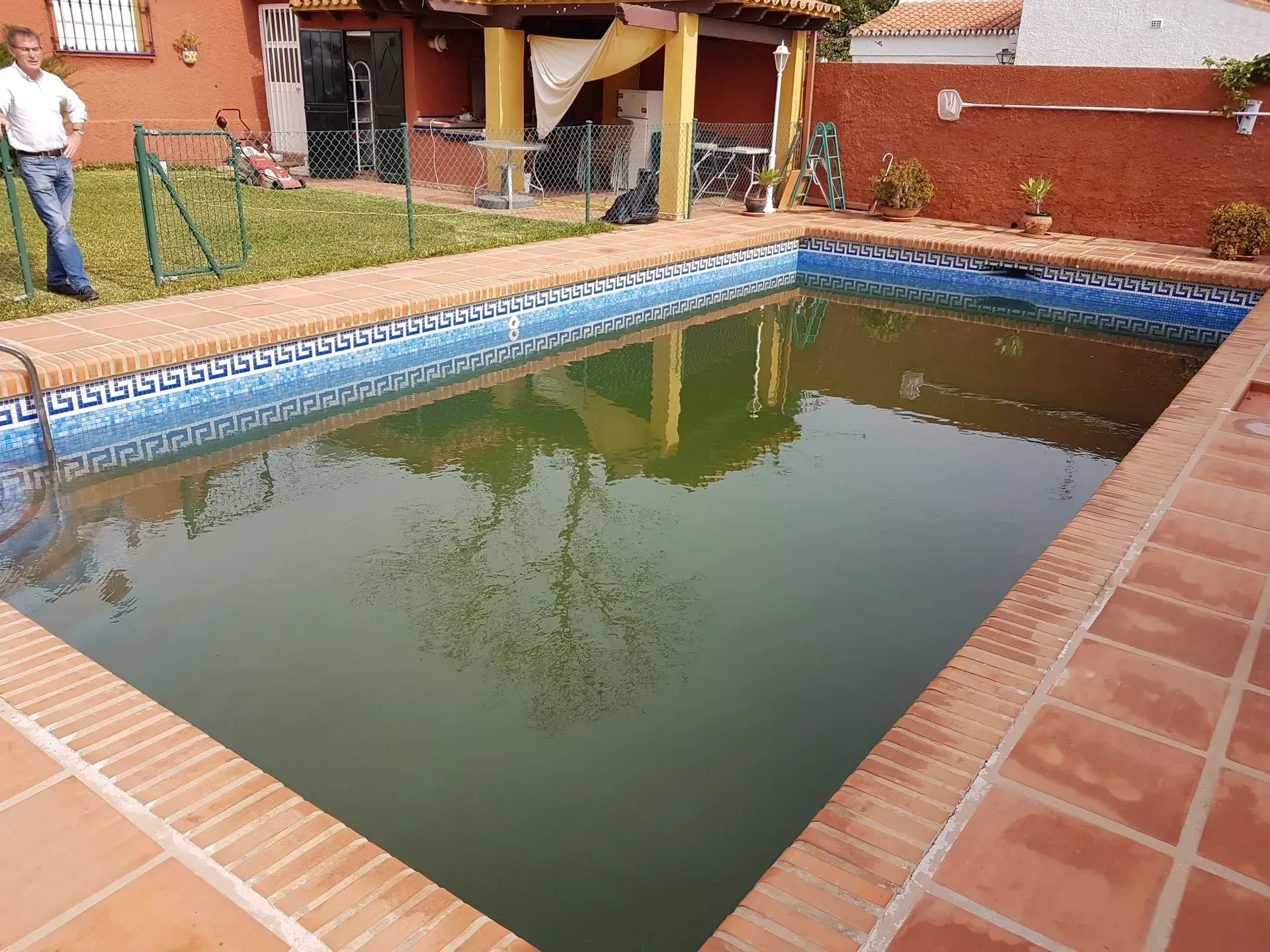Un hombre está de pie junto a una gran piscina.