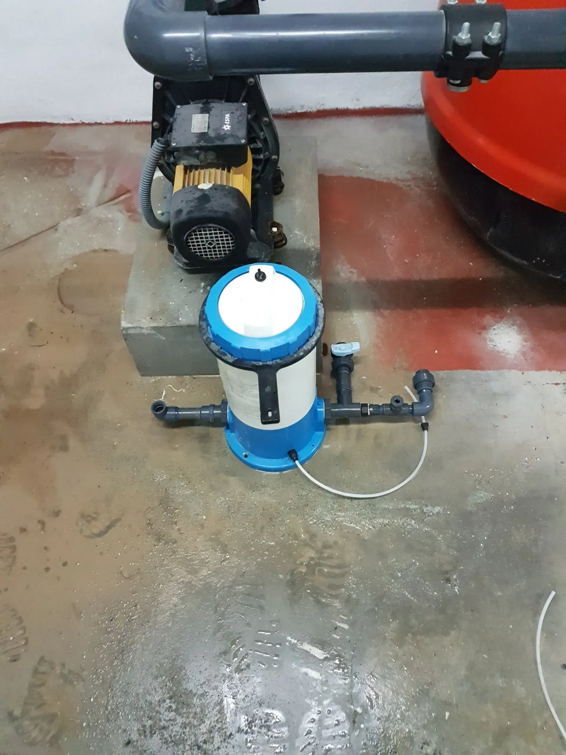 Una bomba azul y blanca está sobre un piso de concreto.