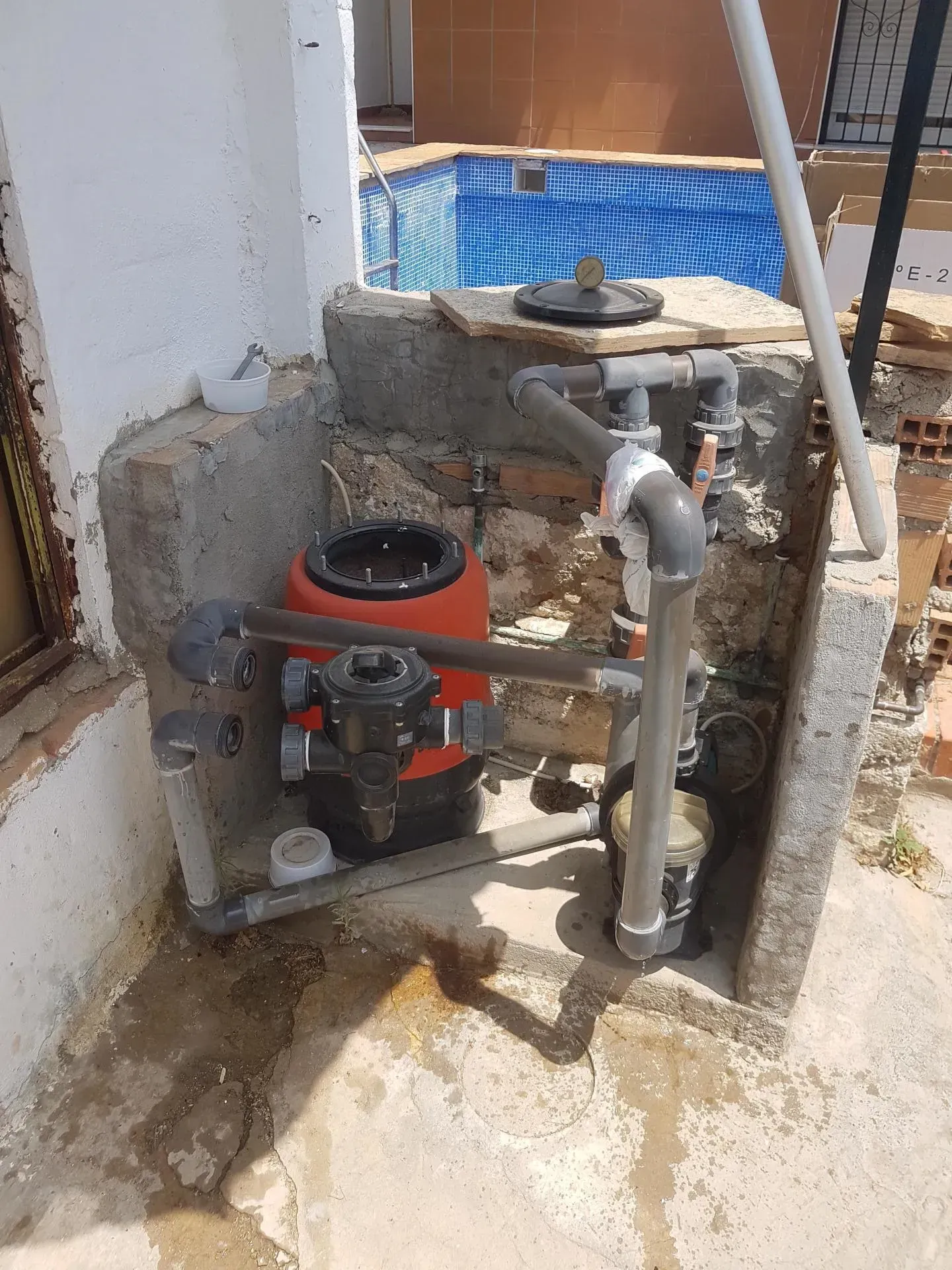 Un filtro de piscina está situado en el lateral de un edificio al lado de una piscina.