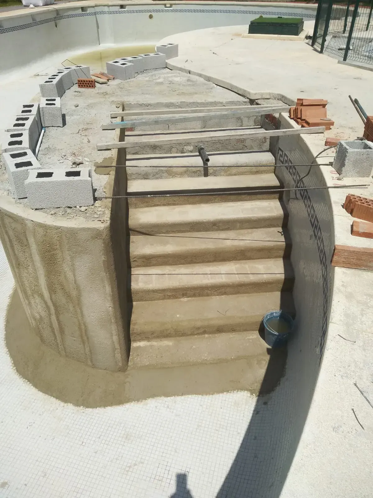 Se está construyendo una escalera de hormigón junto a una piscina.