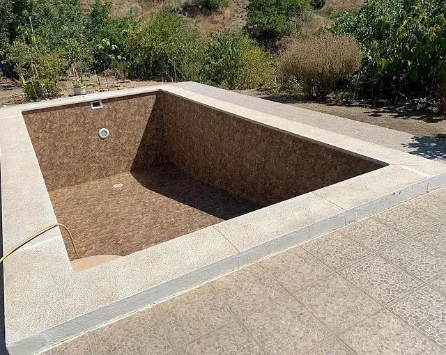 Una gran piscina está situada encima de un patio de hormigón.