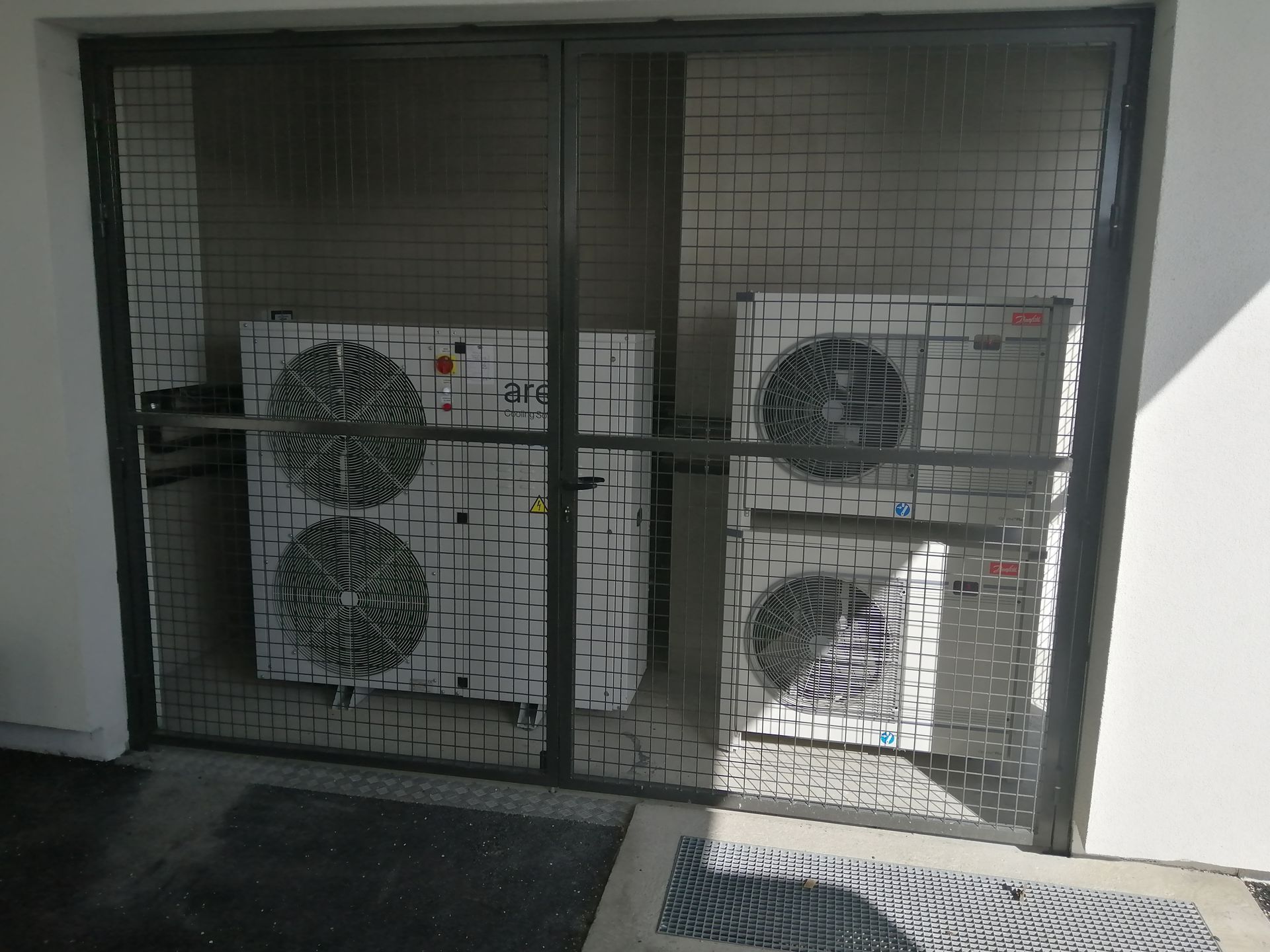 Blocs extérieurs de climatisation derrière un grillage