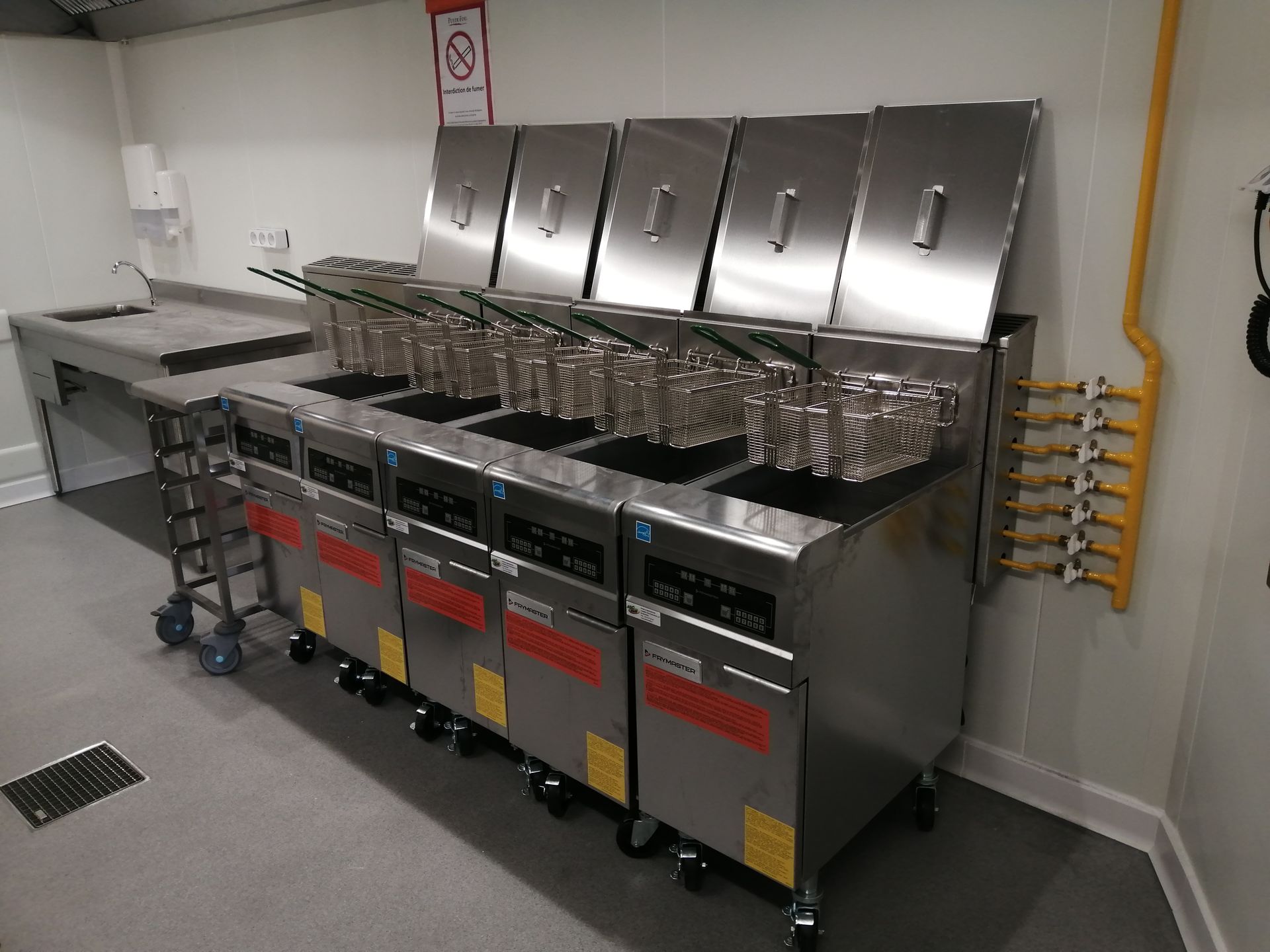 Cinq friteuses alignées dans une cuisine professionnelle