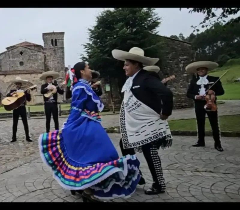 Bailarines folclóricos con coloridos trajes tradicionales actúan al aire libre en un patio.