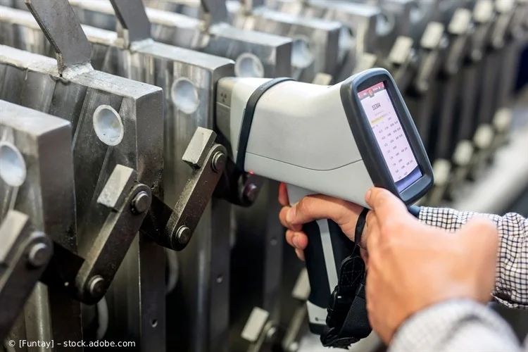 Arbeiter scannt Maschinenteile mit einem handgeführten Barcode-Scanner in einer industriellen Umgebung
