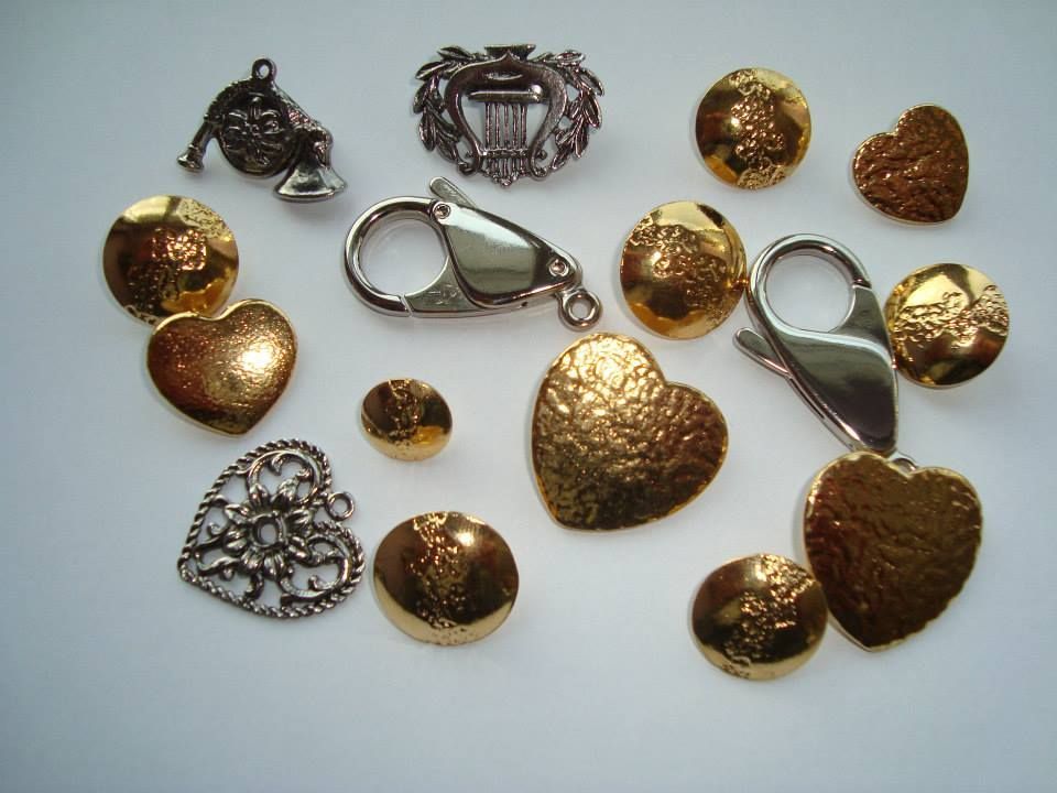 Verschiedene herzförmige Anhänger und Ziernadeln aus Gold und Silber auf hellem Hintergrund