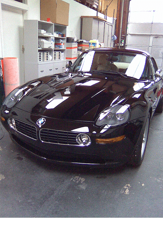 Ein schwarzer BMW Z8 Sportwagen steht in einer Garage und spiegelt das Licht der Deckenbeleuchtung.