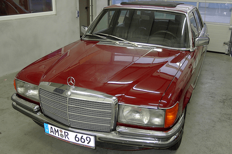 Rote Mercedes-Benz Limousine mit Chromakzenten, Kennzeichen sichtbar, in einer Garage geparkt.