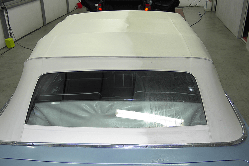 Ein Cabriolet mit weißem Verdeck und durchsichtiger Heckscheibe.