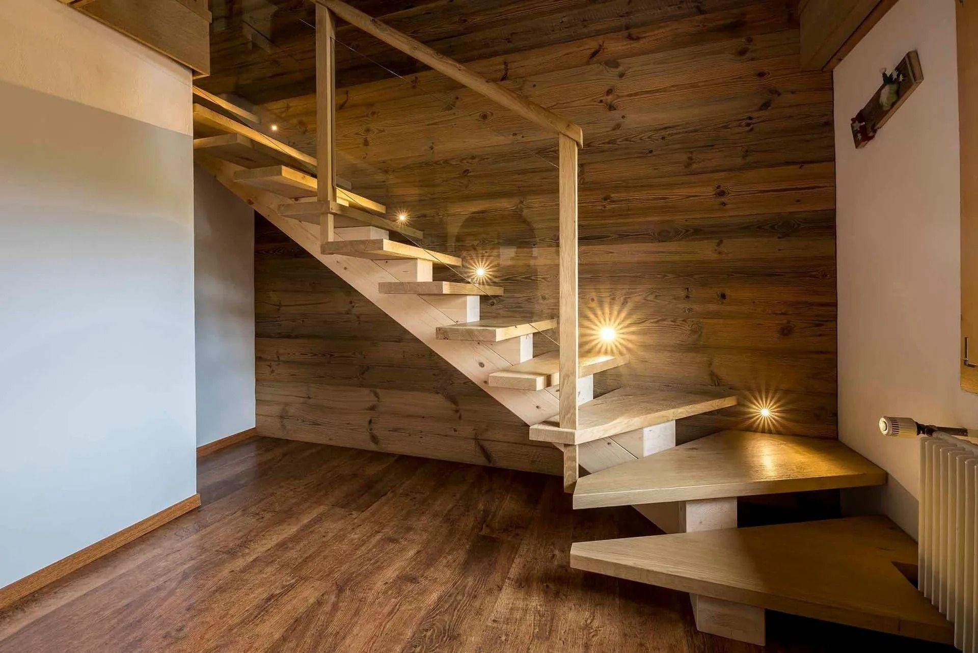 Escalier en bois avec éclairage intégré, adossé à un mur en planches de bois.
