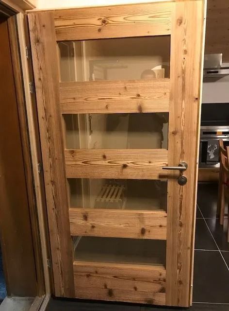 Porte en bois avec quatre panneaux de verre et une poignée argentée.