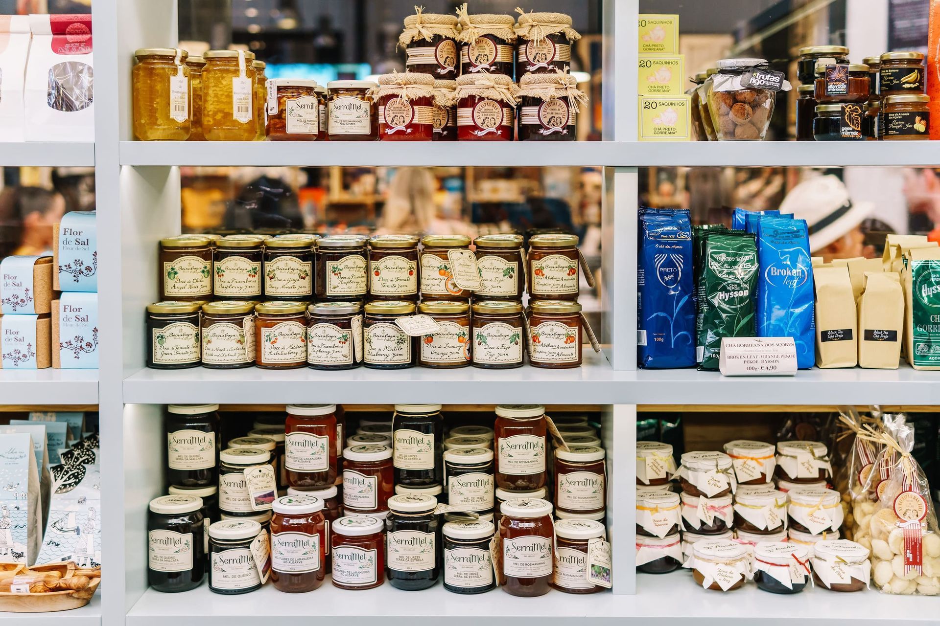 Estantes de un mercado repletos de diversos frascos de vidrio con mermeladas, untables y productos envasados, organizados en filas ordenadas.