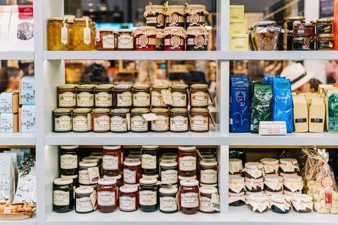 Estantes de un mercado repletos de diversos frascos de vidrio con mermeladas, untables y productos envasados, organizados en filas ordenadas.