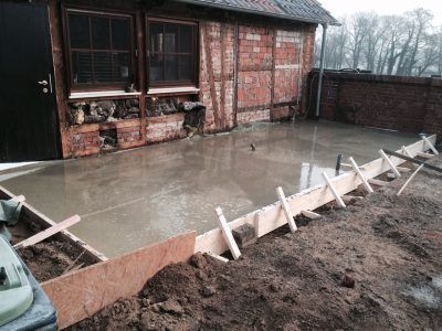 Frischer Beton wurde in einen Innenhof gegossen, ein Holzrahmenbau und ein Gebäude aus Ziegeln und Holz.