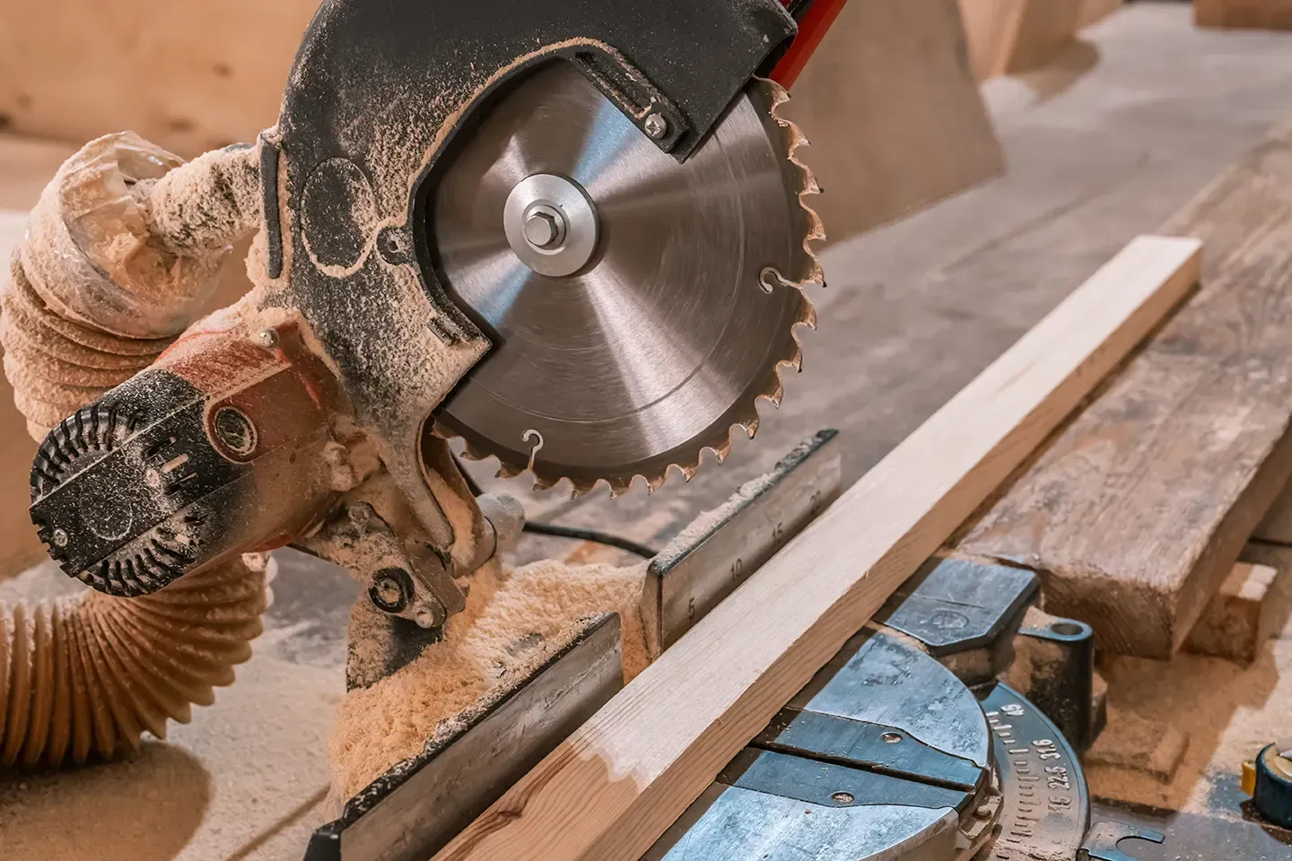Gehrungssäge schneidet ein Stück Holz, Sägemehl sichtbar.