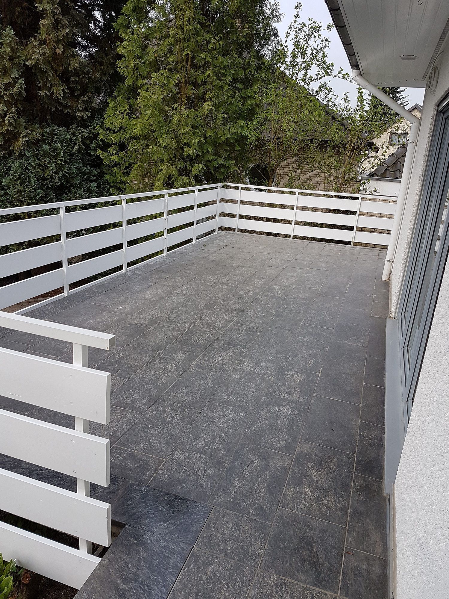 Terrasse mit alten brüchigen grauen Fliesen im Vorher Zustand.