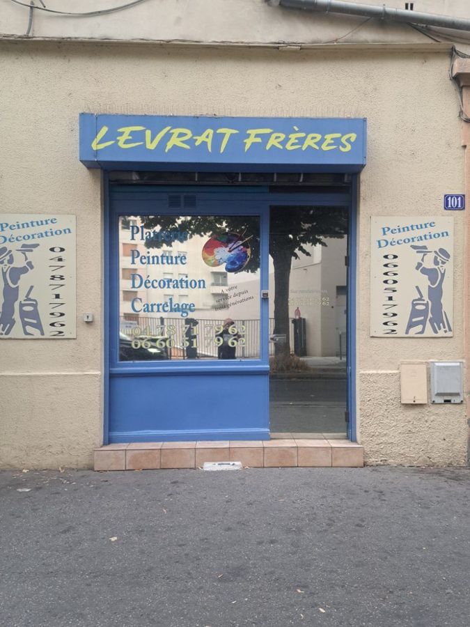 Façade bleue du magasin « Levrat Frères » avec une vitrine présentant des pâtisseries et des décorations.