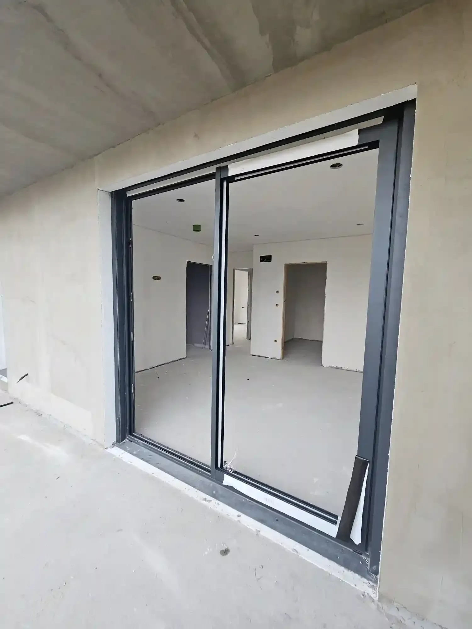 Puertas corredizas de vidrio que dan a una habitación vacía y sin terminar.